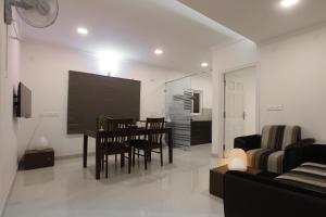 uma sala de estar com uma mesa e cadeiras e uma televisão em Livi Suites - Premium 1 BHK Serviced Apartments em Bangalore