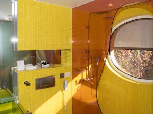 ein Badezimmer mit gelb gefliesten Wänden und einem Fenster in der Unterkunft Semiramis, a Member of Design Hotels in Athen