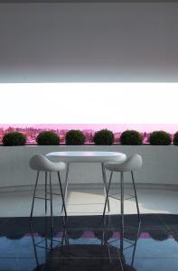 Biały stół i dwa stołki przed oknem w obiekcie Semiramis w Atenach