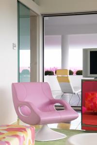 a pink chair in a living room with a tv at Semiramis in Athens