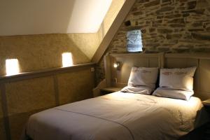 1 dormitorio con 1 cama con pared de piedra en Au gré du Marais - Chambres d'hôtes en Ancenis