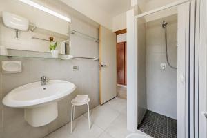 a white bathroom with a sink and a shower at I Giardini di Athena- Athena Resort in Scoglitti
