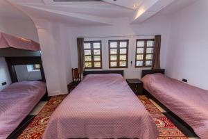Hotel Ajka في بيرات: سريرين في غرفة بها نافذتين
