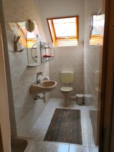 een badkamer met een wastafel, een toilet en een raam bij Holiday Home Scamard in Zamárdi