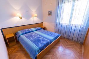 a small bedroom with a bed and a window at Apartments Helena, Mali Lošinj in Mali Lošinj