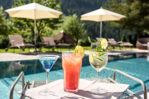 Trzy koktajle na stole obok basenu w obiekcie Hotel Marten - Joker Card Partner w Saalbach Hinterglemm