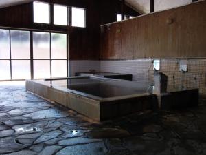 a large bath tub in a room with windows at 布引観音温泉 in Ōhinata
