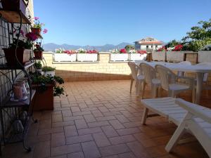 a patio with white tables and chairs and flowers at Casa Noemi in Sperlonga