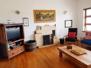a living room with a tv and a table at Norfolkden Beachhouse in Hermanus