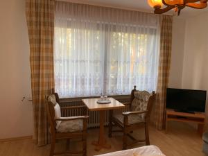 een woonkamer met een tafel en stoelen en een televisie bij Hotel Jeong in Moers