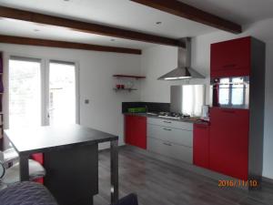 a kitchen with red cabinets and a table in it at mini villa Marcel classée 3 étoiles in Calenzana