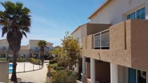 un edificio con una palma accanto a un cortile di Bel appartement confortable et cosy en résidence avec piscine à 5 mn de la mer a Linguizzetta