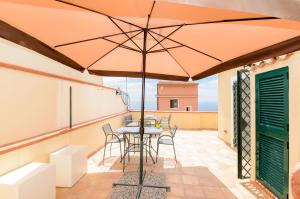 a patio with a table and chairs and an umbrella at Sunset Holiday Home Taormina in Taormina