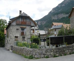 a stone house with a stone wall next to a mountain at Pensión Pallaruelo in Saravillo