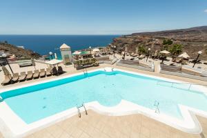 een groot zwembad met de oceaan op de achtergrond bij Holiday Club Vista Amadores in Amadores