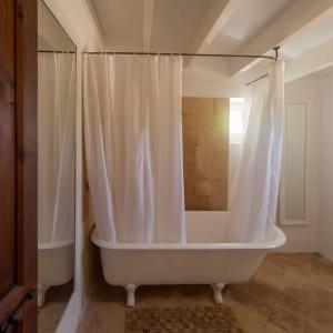 a white bath tub with a shower curtain in a bathroom at Can Toni Platera in Sant Francesc Xavier