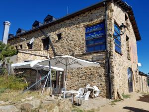 a building with a table and an umbrella in front of it at Convento de Foncebadon in Foncebadón