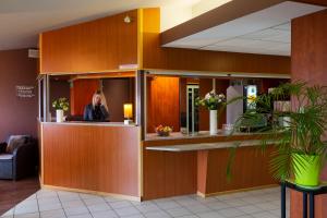 B&B HOTEL Mulhouse Kingersheim في كاجيرْشا: امرأة تجلس في مكتب الاستقبال في غرفة انتظار
