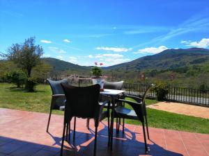 una mesa y sillas en un patio con montañas al fondo en Casa Rural Mirador del Valle, en Cepeda