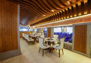 a dining room with tables and white chairs at Bhavanam Regency Guruvayoor in Guruvāyūr