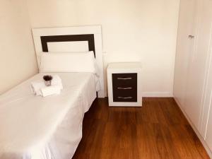 1 dormitorio con cama blanca y mesita de noche en Apartamento Puente Romano P1-1B, en Salamanca