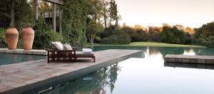 uma cadeira ao lado de uma piscina de água em Saxon Hotel, Villas & Spa em Joanesburgo