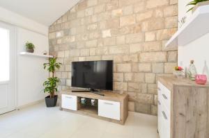 a living room with a television on a brick wall at House Riva in Zavalatica