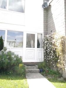 een wit huis met een witte deur en een aantal planten bij Freshwater Bay, 138 in Hodgeston