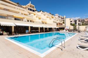 a large swimming pool with chairs and a building at Holiday Club Sol Amadores in Puerto Rico de Gran Canaria