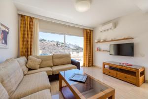 a living room with a couch and a tv at Holiday Club Sol Amadores in Puerto Rico de Gran Canaria