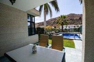 a white table and chairs next to a swimming pool at Sunshine Beach Villas in Puerto Rico de Gran Canaria