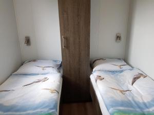 zwei Betten in einem Zimmer, zwischen denen Vögel umherfliegen in der Unterkunft Chalet Veere - eingezäunter Garten, hundefreundlich & ruhig in Zeeland in Serooskerke