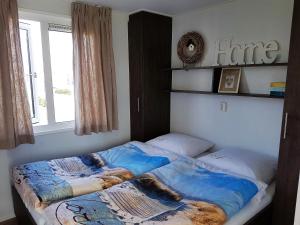 ein Bett in einem Schlafzimmer mit Fenster in der Unterkunft Chalet Veere - eingezäunter Garten, hundefreundlich & ruhig in Zeeland in Serooskerke