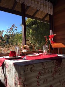 a table with a red and white table cloth and a window at Pousada Oliveri in Monte Verde