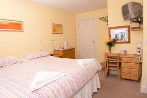 Schlafzimmer mit einem Bett, einer Kommode und einem Schreibtisch in der Unterkunft Holbrook Bed and Breakfast in Shaftesbury