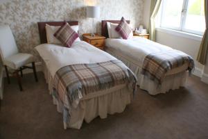 a hotel room with two beds and a chair at Station Hotel Stonehaven in Stonehaven