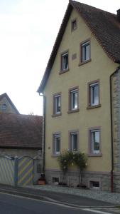 ein gelbes Haus mit braunen Fenstern auf einer Straße in der Unterkunft Ferienwohnung Angelika Gries in Margetshöchheim