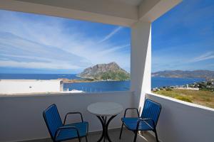 balcón con sillas, mesa y vistas al océano en Studios Aeolos Kalymnos, en Myrties