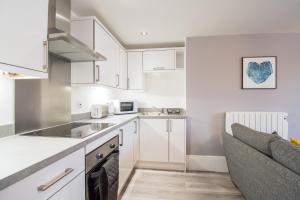 a kitchen with white cabinets and a couch at ONE MOORGATE VIEW in York