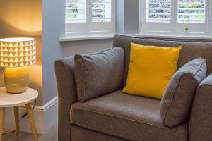 a couch with a yellow pillow and a lamp at One Moorgate View in York