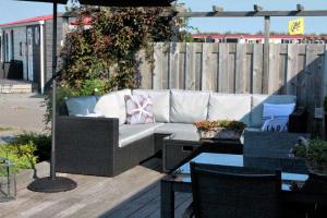 a couch on a deck with a table and an umbrella at Olmenduin Chalet Olm Zeeland in Serooskerke +42 photos