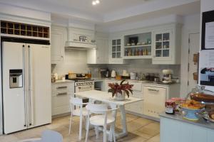 a kitchen with white cabinets and a white table and chairs at Hotel Boutique OMA in Sant Feliu de Guixols