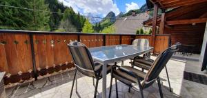 a glass table and chairs on a balcony with mountains at Apartment Alpska Astra in Kranjska Gora
