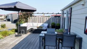 a patio with a table and chairs and an umbrella at Olmenduin Chalet Olm Zeeland in Serooskerke