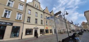 een straat in een stad met gebouwen en mensen op een bankje bij INNY Apartament Rynek Opole in Opole