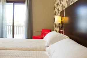 - une chambre avec un lit et une chaise rouge dans l'établissement Hotel Piramide 2, à Portonovo