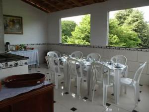 ein Esszimmer mit einem Tisch und weißen Stühlen in der Unterkunft Casa & Hospedagem Carol in Cachoeira Paulista