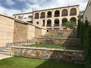 a building with a stone wall and a fence at A Royal Luxury Villa In Center With Two Swimming Pools, Sauna and Jacuzzi. in Yerevan