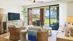 a living room with a television and wicker chairs at Timbers Kauai Ocean Club & Residences in Lihue