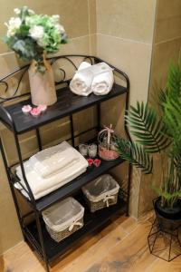 a black shelf with towels and a plant in a bathroom at Aldo Apartments Center in Zadar